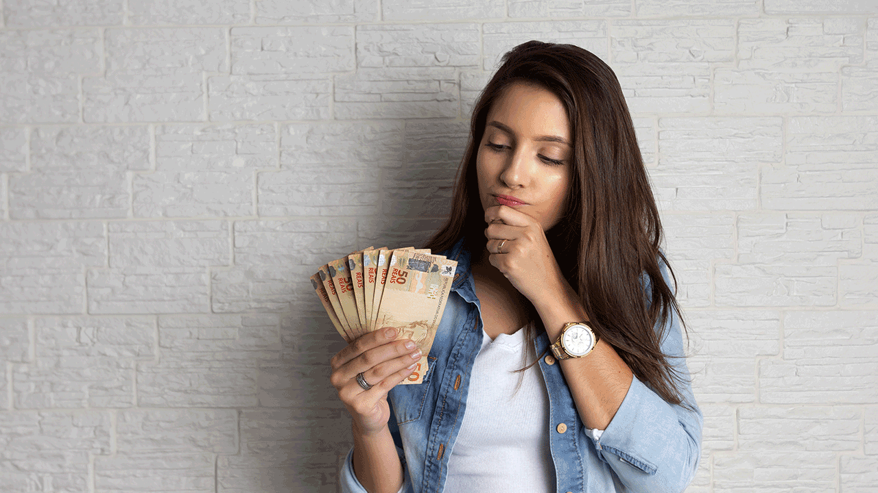 ETF's, investimentos financeiros: mulher observa notas pensando em onde investir seu dinheiro