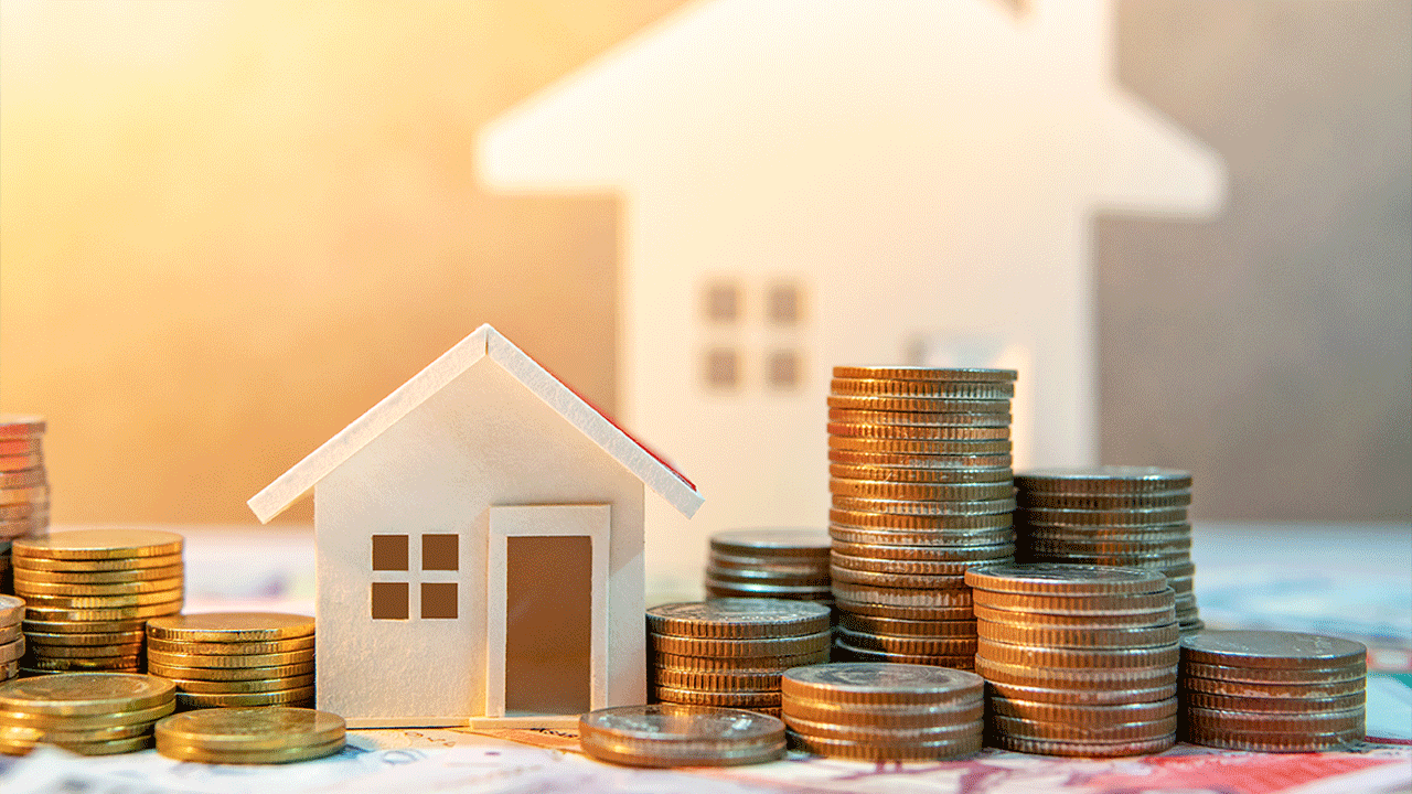 moedas empilhadas ao redor de casas em miniatura, representando investimentos imobiliários