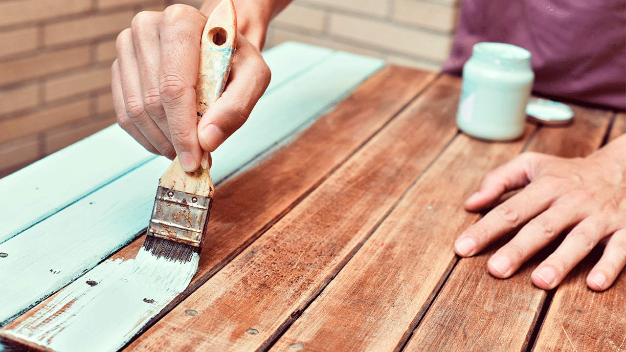 Limpeza de final de ano: homem renova a pintura de uma mesa