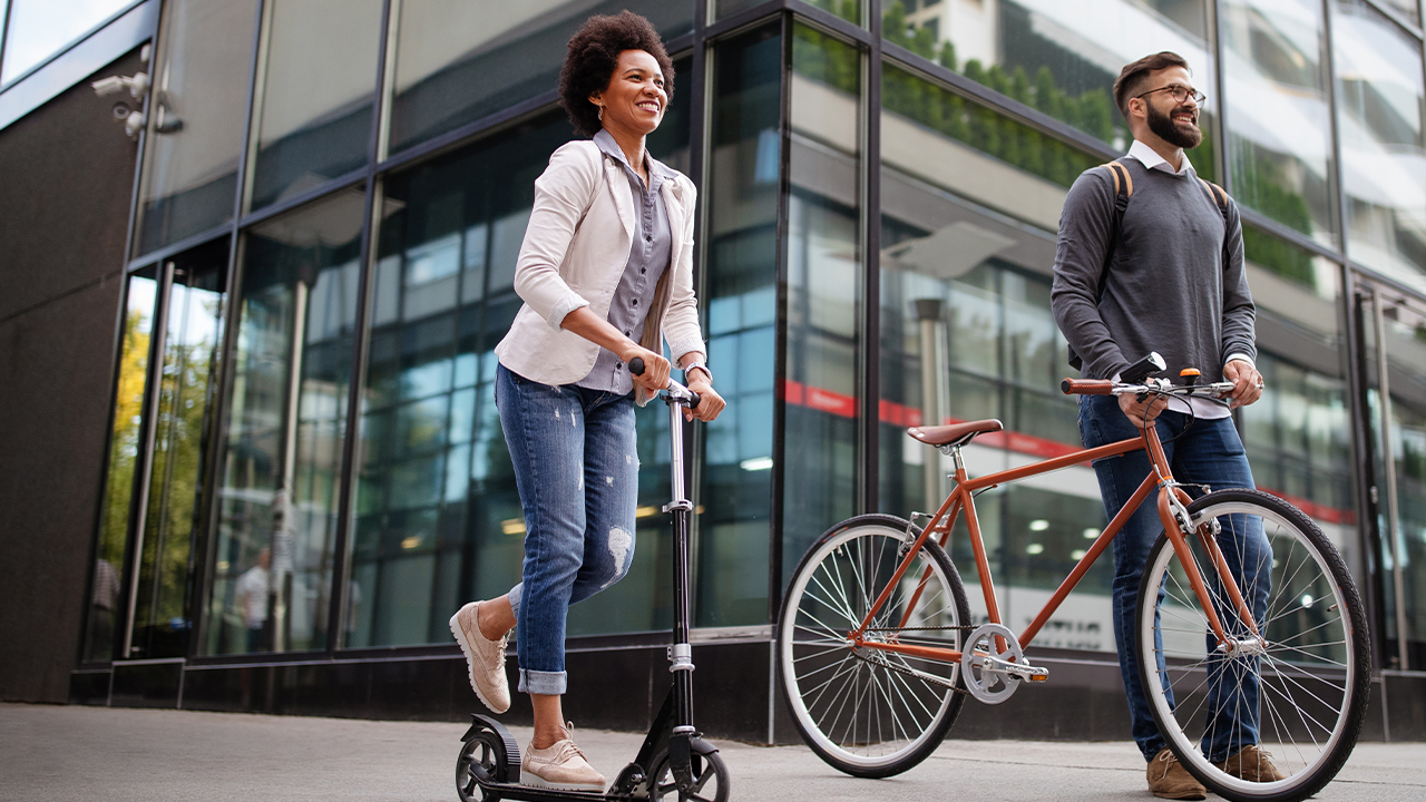 4 situações que devem ser bem planejadas em tempos de inflação alta: homem andando de bicicleta e mulher andando de patinete