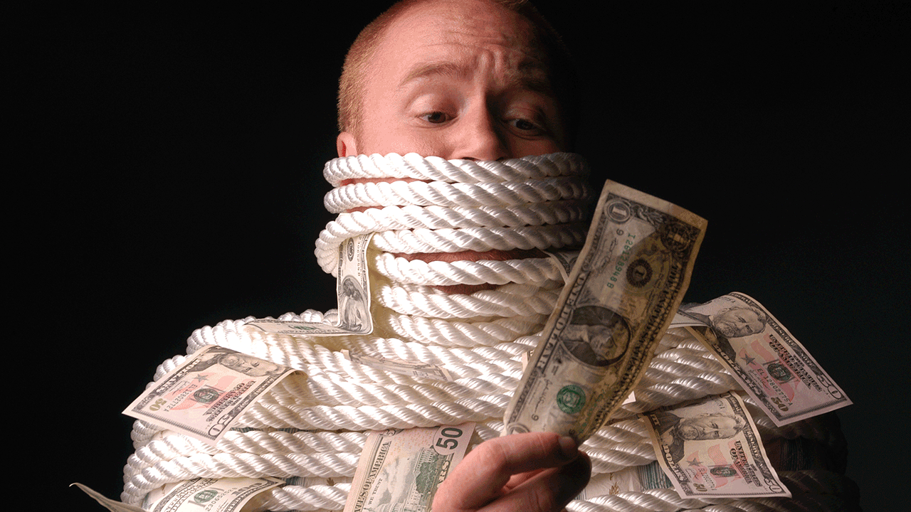 Homem amarrado cercado por notas, representando a fobia financeira