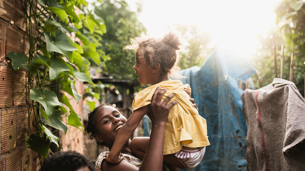Auxílio Brasil: mãe ergue a filha nos braços