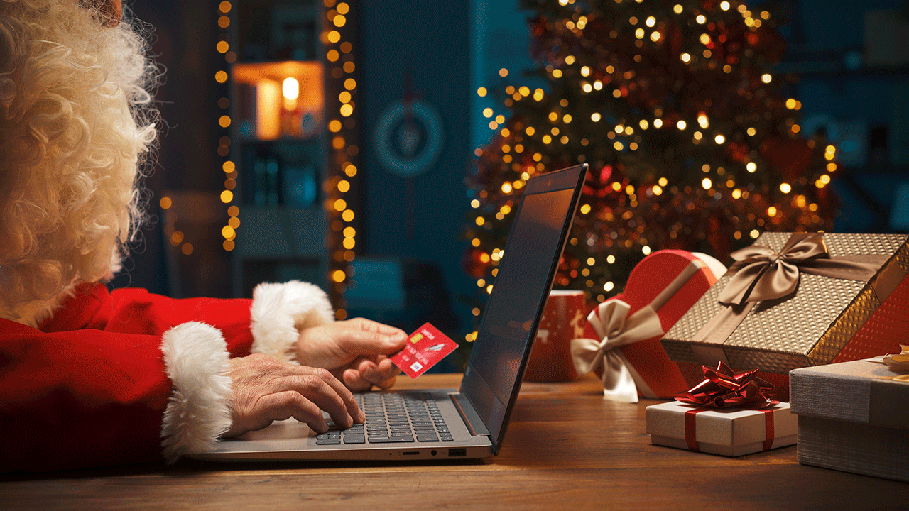 Como preparar o seu negócio para o Natal: papai noel segura um cartão de crédito enquanto faz compras online